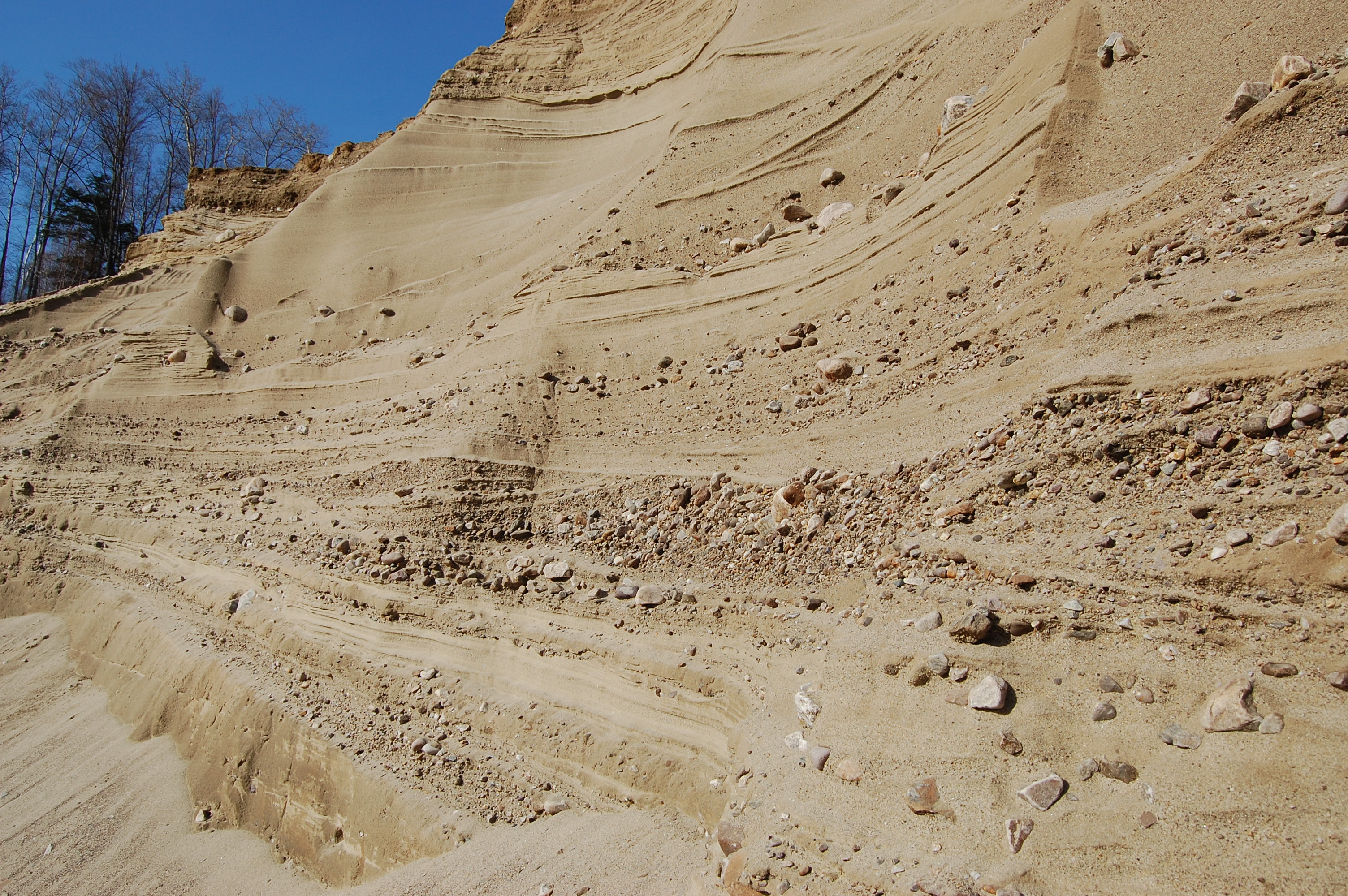 Gravel pit in Vermont showcasing layers of sand and rock, ideal for excavating services.